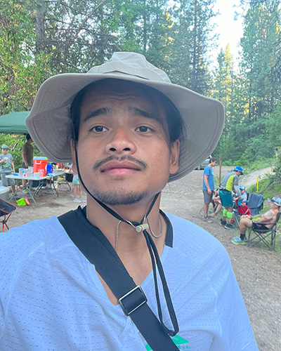Man taking a selfie with aid station volunteers and runners in the background